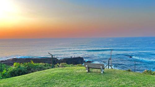 a bench sitting on a hill overlooking the ocean at Benka Beach, Sheffield, KwaZulu Natal in Sheffield Beach