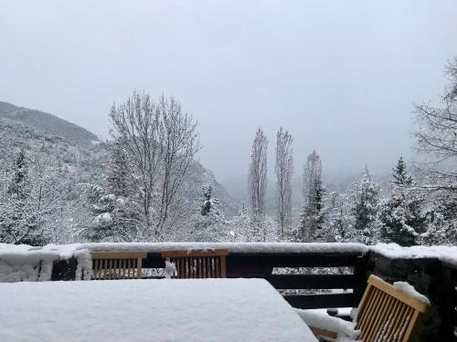 a table covered in snow with two chairs and trees at Chalet Le Tilleul in Valdeblore