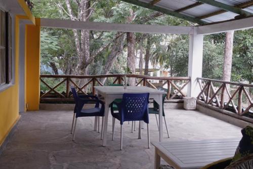 einen Tisch und Stühle auf einer Terrasse mit Bäumen in der Unterkunft Diani Peaceful Garden in Diani Beach