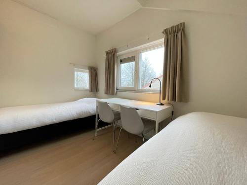 een kamer met 2 bedden, een bureau en een raam bij Watervilla de IJsvogel by Droomvilla in Langweer