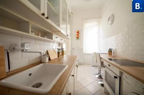 cocina blanca con fregadero y ventana en Jókai Apartment, en Budapest