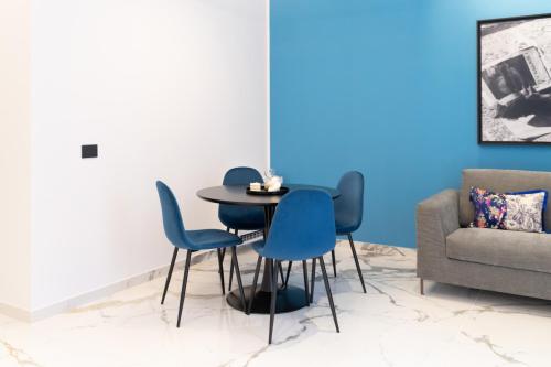 a dining room with blue chairs and a table and a couch at InSogno Suites in Naples