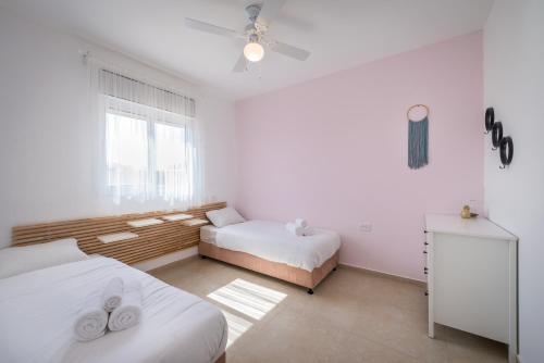 Naẖal Ya‘alonKibbutz Ketura Guest House的一间有两张床和一扇窗户的白色房间