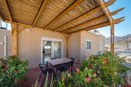 a patio with a table and chairs under a wooden pergola at Kibbutz Ketura Guest House in Naẖal Ya‘alon