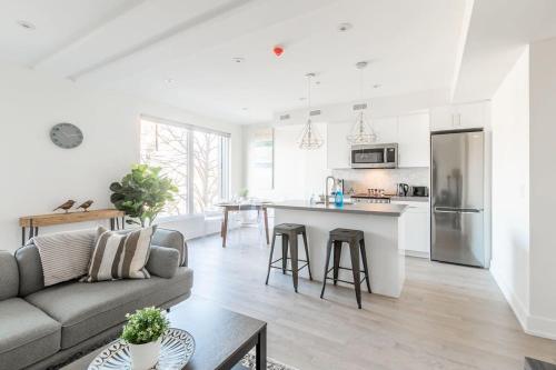 een witte woonkamer met een bank en een keuken bij Bloor West Apartment Near High Park in Toronto