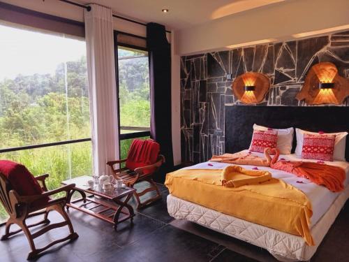 a bedroom with a bed and chairs and a large window at Kandy IVY Mountain View Resort in Kandy