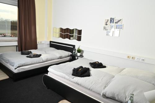two beds in a room with black pillows on them at Pott Hostel - Zimmervermietung in Essen