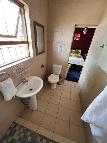 baño con lavabo y aseo y ventana en E.G Guest House, en Kokstad