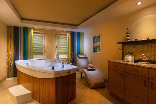 een grote badkamer met een groot bad en een stoel bij IFA Graal-Müritz Hotel & Spa in Graal-Müritz