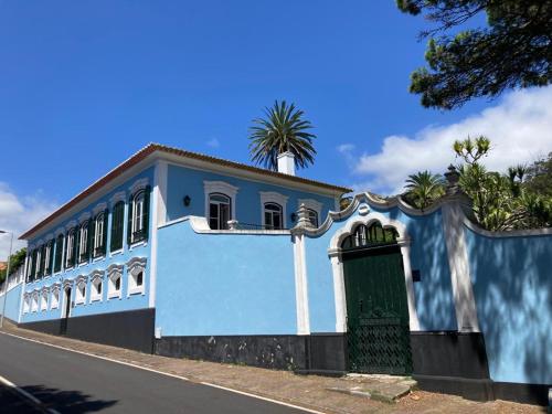 a blue and white building with a green door at Quinta das Palmeiras in Angra do Heroísmo
