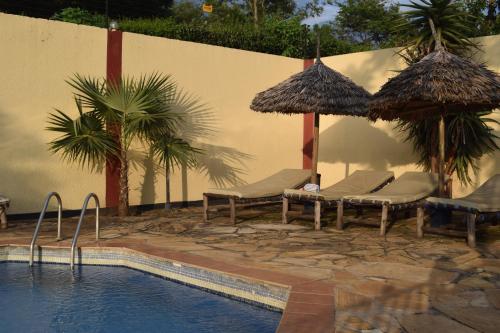 a swimming pool with chairs and umbrellas next to a swimming pool at Stasumo House Arusha in Arusha