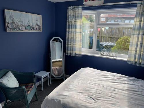 a bedroom with blue walls and a bed and a window at LetAway - Tom's Cabin, Staithes in Staithes
