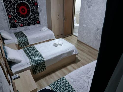 a room with two beds and a door to a bathroom at Elita House Samarkand in Samarkand