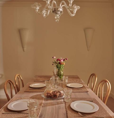 a dining room table with plates and a chandelier at Aghioti in Agios Nikitas