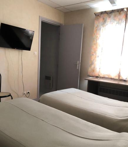 a room with two beds and a television and a window at Hôtel De La Mare -restaurant pour les clients sur réservation in Avrigny