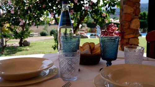 a table with a bottle and some plates and glasses at Hotel Janas in Tertenìa