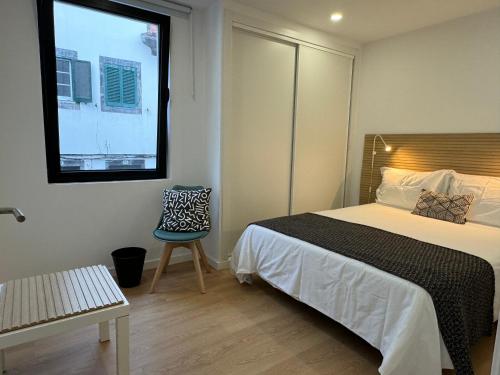 a bedroom with a bed and a chair and a window at Living PDL 2 in Ponta Delgada