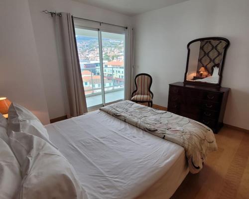 um quarto com uma cama, uma cómoda e um espelho em Nova Madeira Apartment Machico em Machico