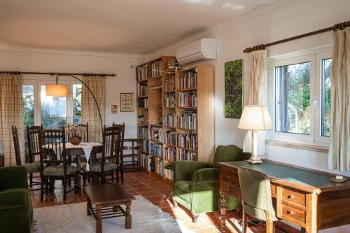 a living room with a library with green chairs and a table at Casa do Magoito in Bolembre de Baixo