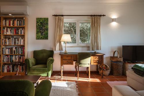 a living room with a desk and chairs and a window at Casa do Magoito in Bolembre de Baixo