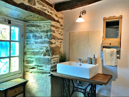 La salle de bains est pourvue d'un lavabo et d'un mur en pierre. dans l'établissement Maison Rocher, à Ségur-le-Château