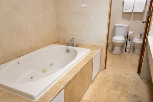 a white bath tub in a bathroom with a toilet at Ciqala Suites Hotel - San Juan in San Juan