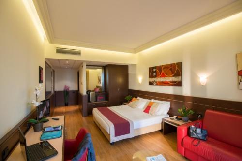 una camera d'albergo con un letto e un divano rosso di As Hotel Cambiago a Cambiago