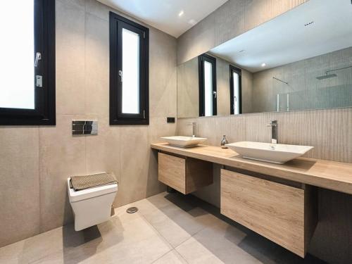 łazienka z 2 umywalkami, toaletą i lustrem w obiekcie Villa Paraiso w parking gym pool lounge cinema w mieście Estepona