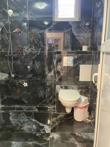 a bathroom with a toilet and a stone wall at CAMERE de INCHIRIAT LA TUGUIATA in Buşteni