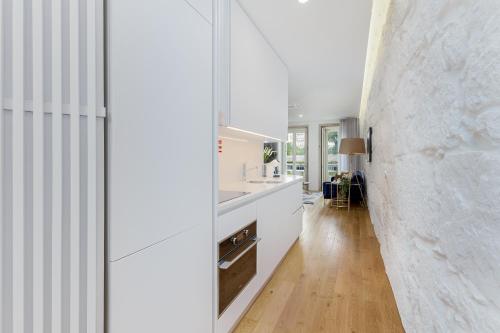 a kitchen with white cabinets and a white wall at In Porto Gallery Guesthouse in Porto