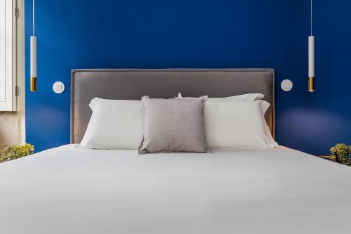a bed with white pillows and a blue wall at In Porto Gallery Guesthouse in Porto