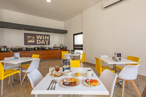 uma sala de jantar com mesas e cadeiras com comida em WinDay Hotel Express em Veracruz