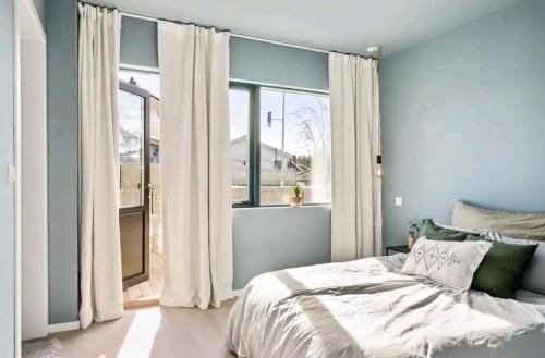 een slaapkamer met een bed en een groot raam bij Modern house near the ocean in Sandefjord