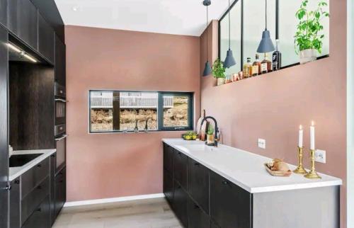 una cucina con pareti rosa e un'ampia isola cucina di Modern house near the ocean a Sandefjord