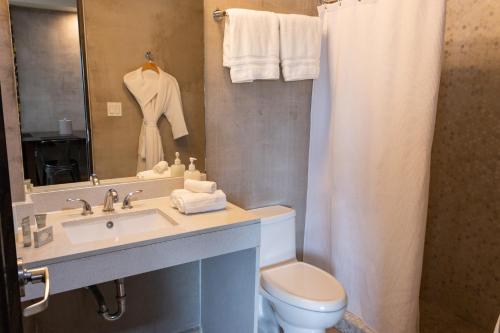 a bathroom with a sink and a toilet and a mirror at Ciqala Suites Hotel - San Juan in San Juan