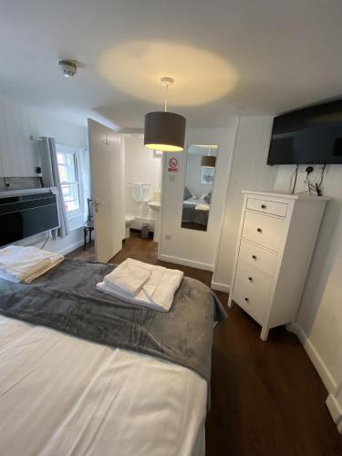 a bedroom with a bed and a dresser and a mirror at Wheatsheaf Hotel in Newport