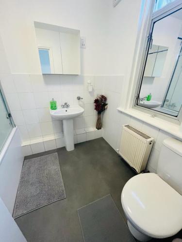 a bathroom with a white toilet and a sink at Stay and Explore Easy Central London Access via Jubilee Line in London