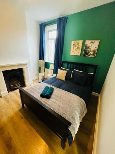 a bedroom with a large bed with a green wall at Stay and Explore Easy Central London Access via Jubilee Line in London