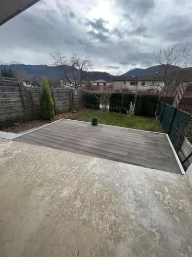 a concrete patio in a yard with a fence at Maison avec terrasse et garage proche tram in Gières