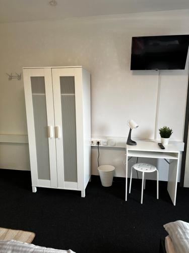 a bedroom with a desk and a white cabinet at Pott Hostel - Zimmervermietung in Essen