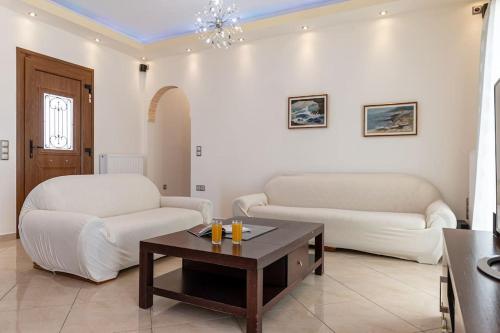 a living room with two white couches and a coffee table at Gavriella House in Mélanes