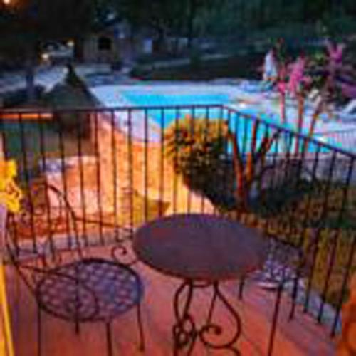 a balcony with a table and chairs next to a pool at Hôtel Lou Caleù restaurant le Rocher des Abeilles in Saint-Martin-de-Castillon