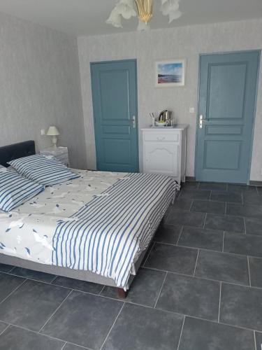 a bedroom with a bed with blue doors and tile floors at la pêcherie bord de mer in La Plaine-sur-Mer