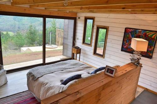 a bedroom with a large bed and large windows at Casa en Lago Vichuquén, sector la queseria. in Llico