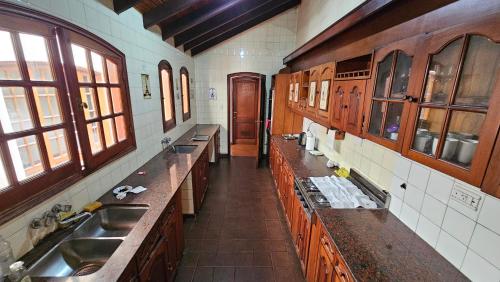 a large kitchen with wooden cabinets and sinks and windows at Valhalla Hostel & Suites in Salta