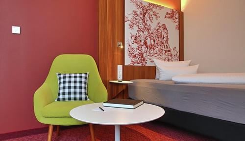 IBB Hotel Ingelheim في إنجلهايم أم راين: غرفة نوم بسرير وكرسي أخضر وطاولة