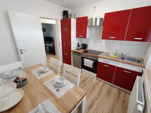 une cuisine avec des placards rouges, une table et des chaises dans l'établissement Ferienwohnung am Rathaus, à Landstuhl