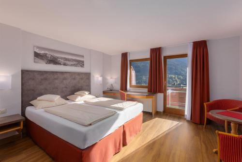 una habitación de hotel con una cama grande y una mesa en IFA Alpenrose Hotel Kleinwalsertal en Mittelberg