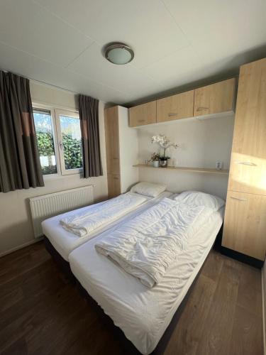 a large white bed in a room with a window at Chalet 102 in Voorthuizen