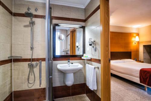 a bathroom with a shower and a sink and a bed at Hotel Alda Bonaval in Santiago de Compostela